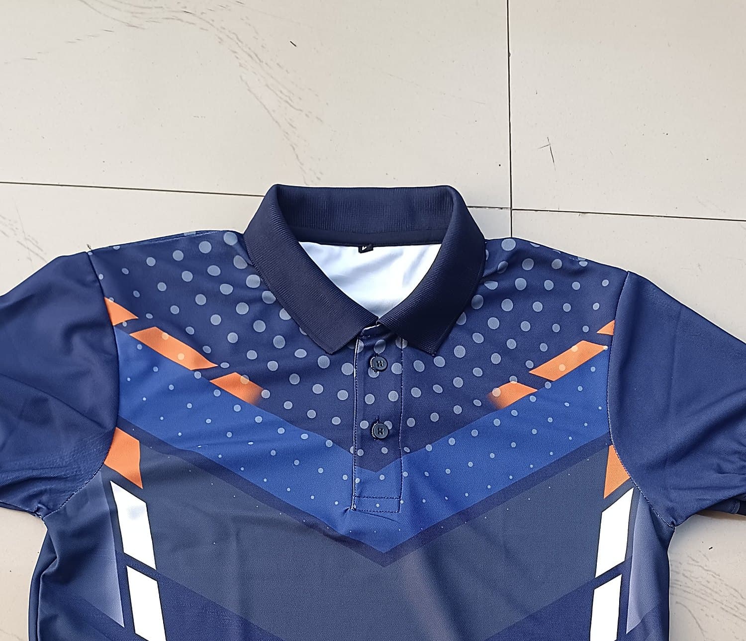Navy sublimated sports polo laid flat, showing the printed yoke and knitted collar