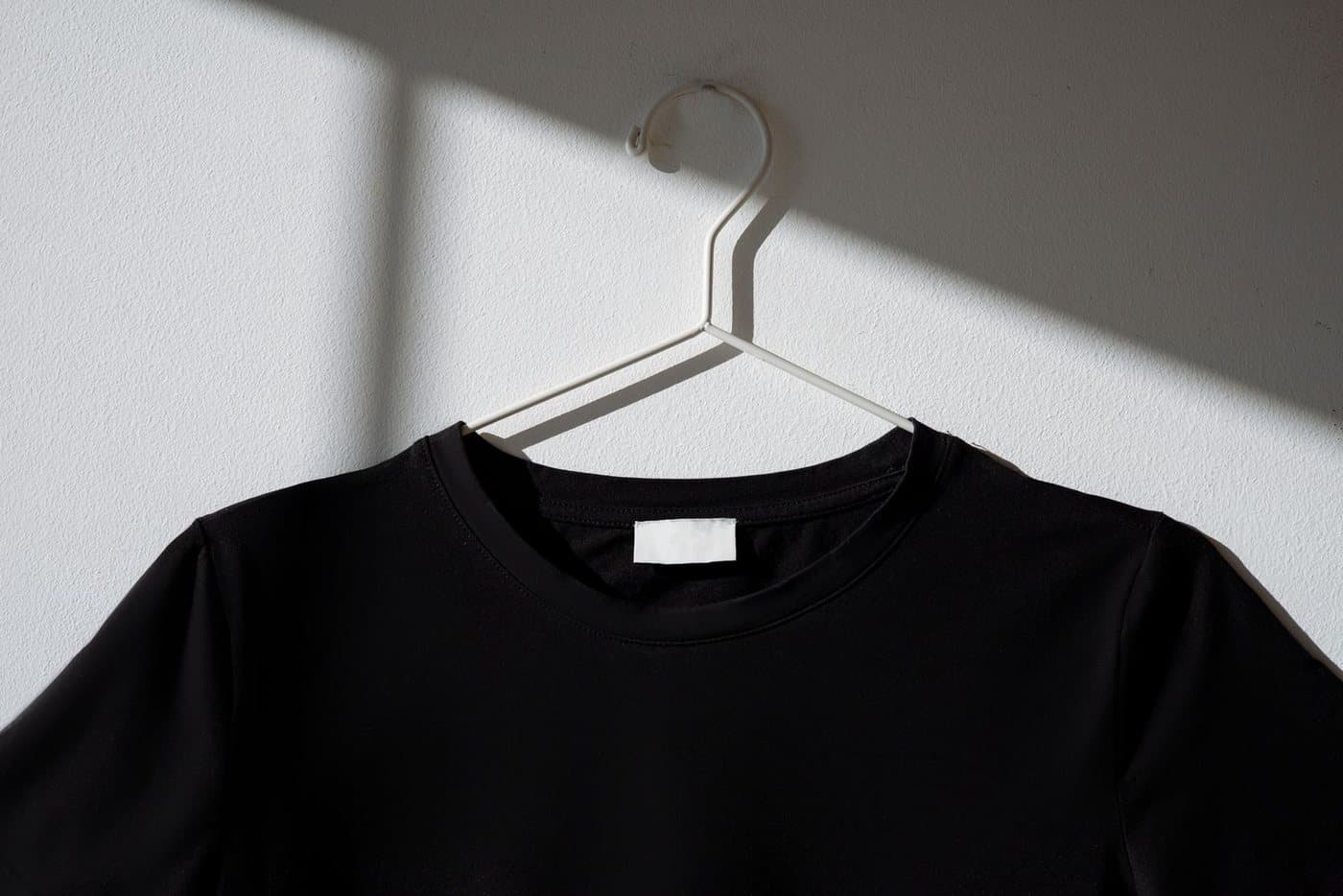 Plain black cotton T-shirt on a hanger